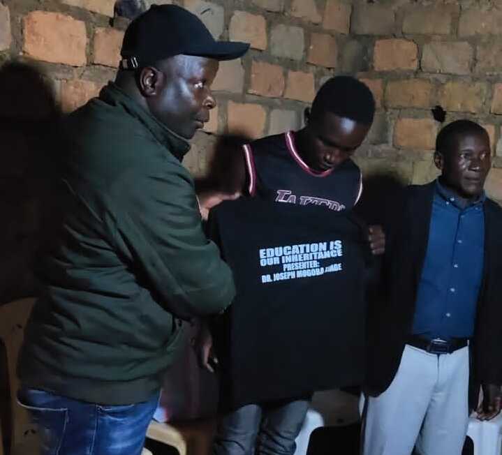 chairman dr joseph mogoba handing a uniform a student
